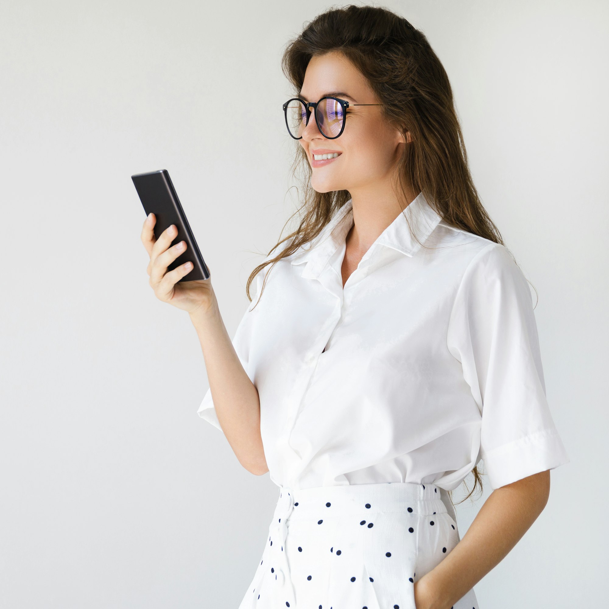 Young businesswoman is using smartphone on gray background